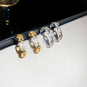 Macro shot of gold and silver chain link C-shape earrings with sparkling cubic zirconia