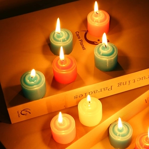 Colorful round tea light candles in blue and white on books with warm flame
