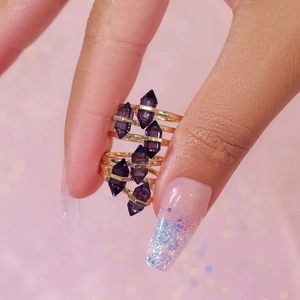 Close-up of gold layered ring with purple geometric crystals on a soft background