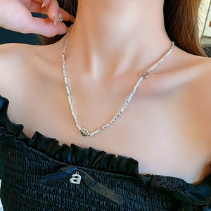Close-up of a silver smiley face charm necklace on a model for daily fashion look