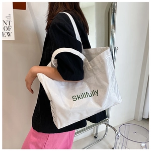 Detail view of a white large PVC tote bag with Skillfully print worn by a model