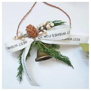 Detail of pine cone Christmas ornament with bronze bell and white berry accents