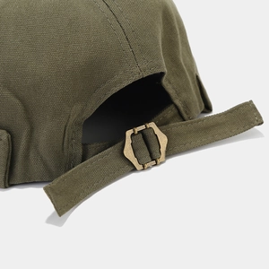Détail de la boucle métallique et de la sangle en toile sur la casquette verte