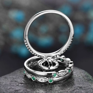 Macro detail of three-piece silver ring set with green emeralds and pavé crystals