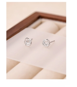 Macro detail of S999 silver hollow rose stud earrings on a premium jewelry display stand
