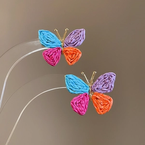 Macro detail of colorful pleated butterfly earrings with vibrant wings and gold metal body