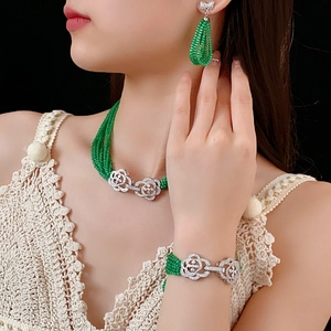 Detail of green beaded jewelry set with floral silver clasps worn by a model