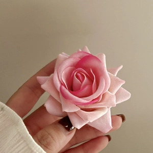 Close-up of a pink fabric rose hair clip showing delicate layered petals and textures