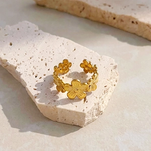 Detail of 18K gold stainless steel flower ring on a natural stone surface