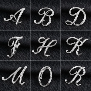 Detailed close-up of silver alphabet brooches with crystals in a 3x3 grid display