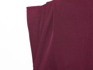Close-up of pleated dark red fabric showing fine plain weave texture and smooth drape