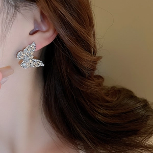 Close-up of sparkling silver butterfly earrings with crystals worn by a model