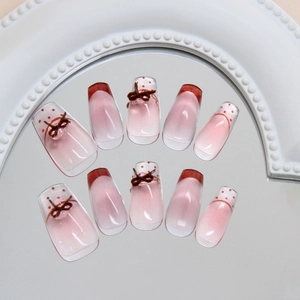 Pink cat eye press-on nails with 3D bows and polka dots in a French tip style