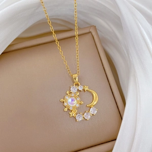 Golden sun and moon necklace with opal and zircons on elegant white silk background