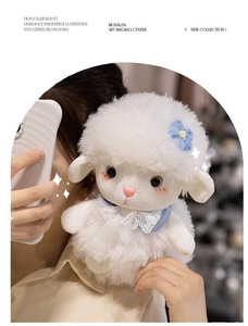 Close-up of a plush white sheep doll featuring a blue flower and lace bow tie detail