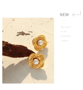 Detail of vintage gold flower petal stud earrings with white pearl centers on wood décor