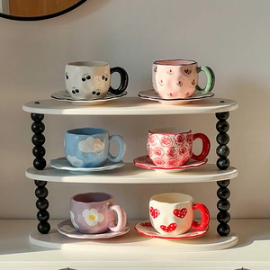 Handcrafted ceramic coffee cup and saucer sets with hand-painted patterns on a display shelf
