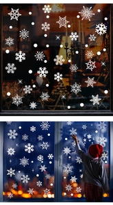 Close-up of white snowflake window clings with festive decorations and a child model