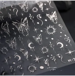 Detail macro view of 3D silver metallic nail stickers with butterfly and moon patterns