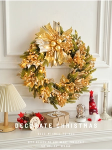 Close-up of 50cm green Christmas wreath with gold bows and warm LED lights on a white wall