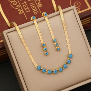 Golden snake chain necklace and earring set with blue evil eye beads on a display box