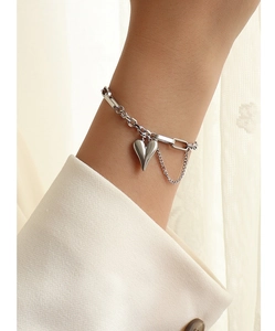 Close-up of silver heart charm bracelet with paperclip chain on female model