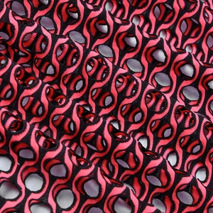 Détail de tissu en maille rouge et noir avec motifs circulaires ajourés pour maillots