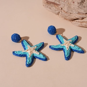 Dettaglio di orecchini a stella marina in rafia intrecciata blu e bianca con perni