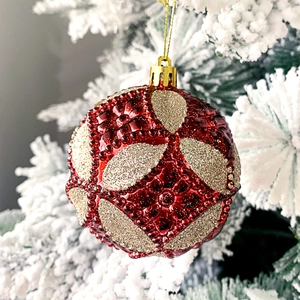 Nahaufnahme einer roten Weihnachtskugel mit goldenen Glitzermustern und Perlenverzierung