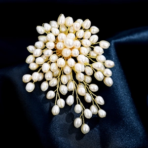 Detailed macro of handmade natural freshwater pearl brooch on dark blue silk fabric