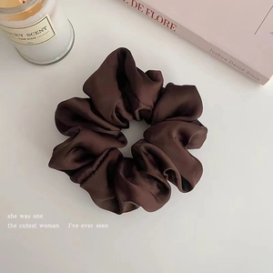 Close-up of a dark brown satin scrunchie with silky texture for hair styling