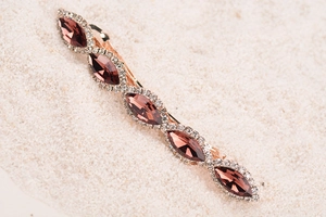 Macro shot of pink oval gemstones and sparkling rhinestones on a metal hair clip