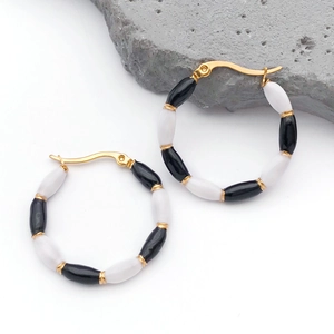Detailed view of bamboo style gold hoop earrings with black and white enamel beads