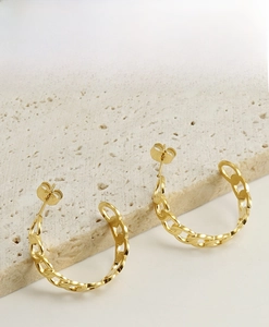 Macro shot of 18K gold plated interlocking chain earrings on a textured stone