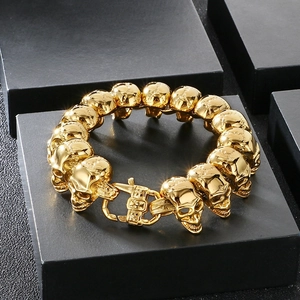 Macro shot of a polished golden stainless steel bracelet featuring detailed skull links