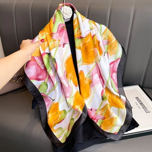 Detail view of large floral print satin scarf in yellow and pink with black borders