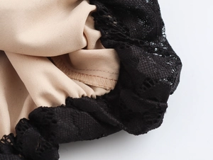 Dettaglio di pizzo nero con fodera beige e cuciture sull'abito con scollo quadrato