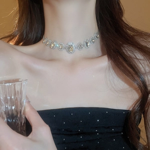 Silver choker necklace with oval crystal link detail on a female model with black dress