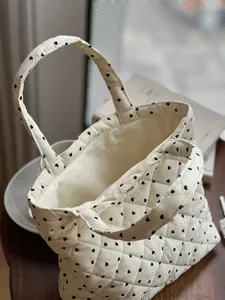 Gros plan d'un sac à main matelassé blanc en velours côtelé avec des motifs de cœurs noirs