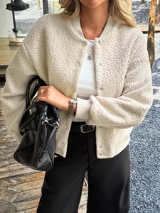 Detail of cream-colored sherpa fleece jacket with snap buttons and ribbed cuffs