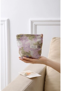 Détail d'une trousse à maquillage jacquard violette avec fermeture fleurie et logo