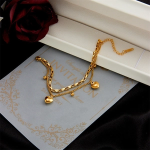 Double-layered gold heart pendant bracelet with round beads on elegant gift card