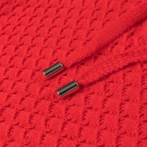 Vue macro détaillée d'un tricot nid d'abeille rouge avec des embouts de cordon en métal argenté