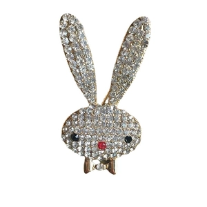 Sparkling rabbit head brooch with white rhinestones and gold bow on white background