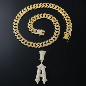 Détail de la chaîne cubaine dorée avec pendentif luxueux lettre A gothique serti de strass
