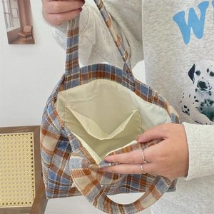 Macro detail of the plaid tote bag interior showing beige lining and two inner pockets