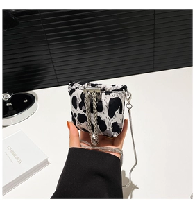 Close-up of leopard print mini crossbody bag with silver chain strap held in hand