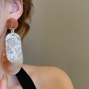 Gros plan de boucles d'oreilles géométriques en acrylique à texture marbrée