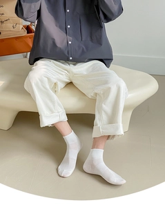 Detail showing white striped cotton socks paired with white corduroy rolled-up trousers
