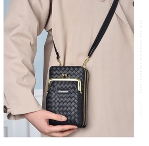 Détail du sac de téléphone noir tressé avec boucle dorée porté sur un trench-coat chic